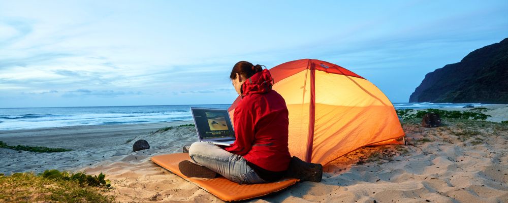 Woman sitting next to tent on beach 